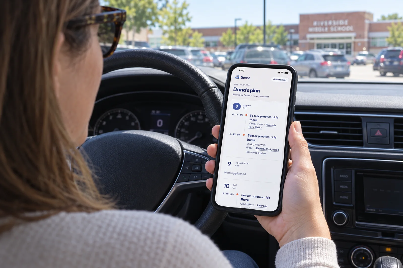 A parent parked at school pickup reading Dana's plan on her phone: a ride to soccer practice and a ride home that still needs a driver