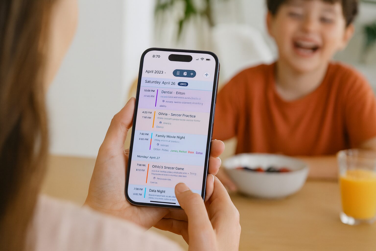 A mother checks the family's week on the Sense calendar while her kids laugh over breakfast