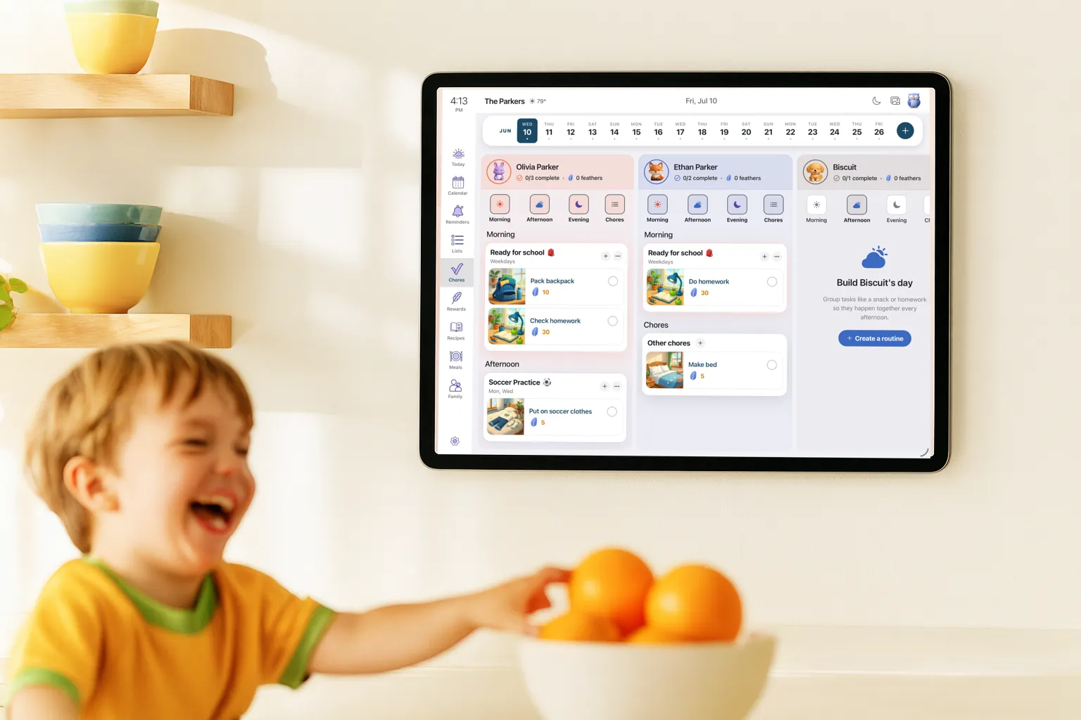A laughing child in front of a wall-mounted tablet showing each child's morning and afternoon routines with picture cards