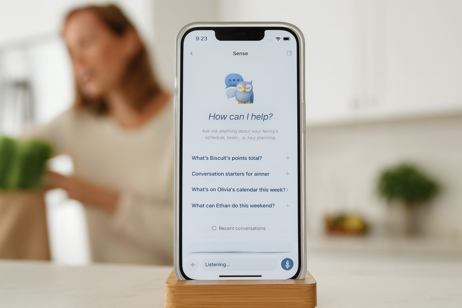 A mom unpacking groceries speaks to Sense on a propped-up phone showing the listening voice assistant